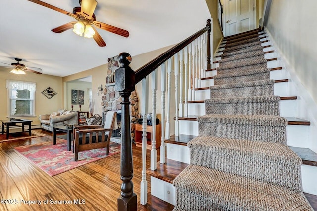 stairs featuring ceiling fan and hardwood / wood-style flooring