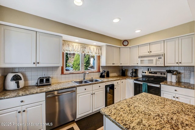 kitchen featuring stainless steel appliances, sink, white cabinets, decorative backsplash, and wine cooler