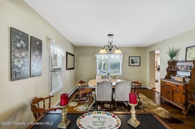 dining space featuring a notable chandelier, dark wood-type flooring, and a baseboard heating unit