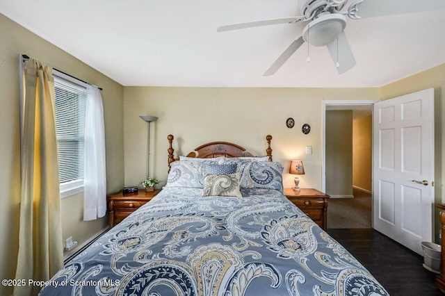 bedroom featuring ceiling fan, multiple windows, and dark hardwood / wood-style floors