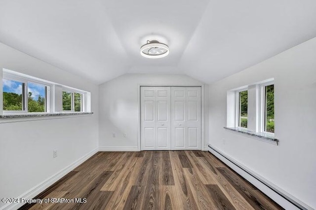 unfurnished bedroom with a baseboard radiator, a closet, lofted ceiling, and dark hardwood / wood-style floors