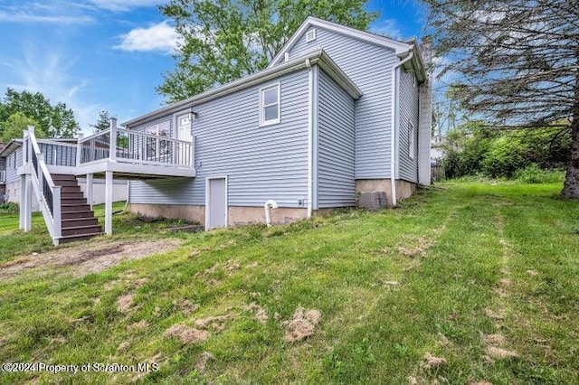 rear view of house featuring a lawn and a deck