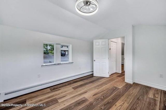 unfurnished bedroom with wood-type flooring, lofted ceiling, and baseboard heating