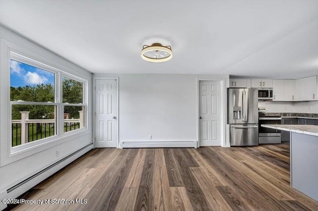 kitchen featuring white cabinets, hardwood / wood-style flooring, appliances with stainless steel finishes, and a baseboard radiator