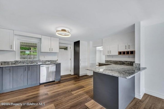 kitchen with white cabinets, dark hardwood / wood-style flooring, stone countertops, and stainless steel dishwasher