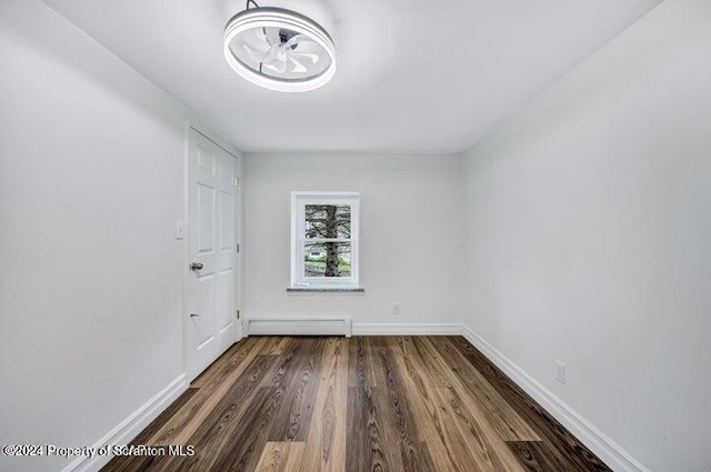 empty room featuring wood-type flooring and baseboard heating