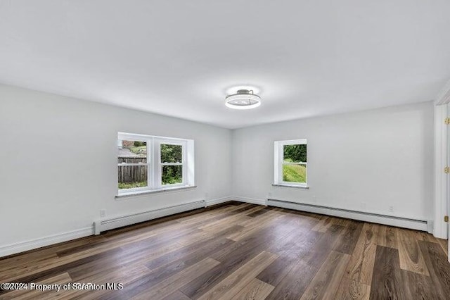 empty room featuring baseboard heating and dark wood-type flooring