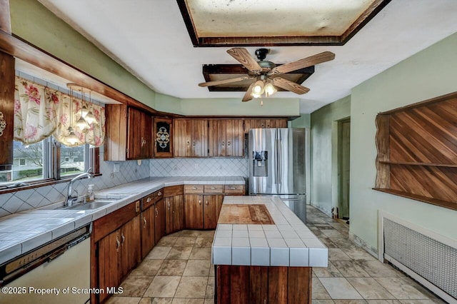 kitchen with tile counters, radiator heating unit, dishwasher, stainless steel refrigerator with ice dispenser, and decorative backsplash