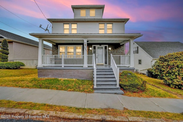american foursquare style home featuring covered porch and a front lawn