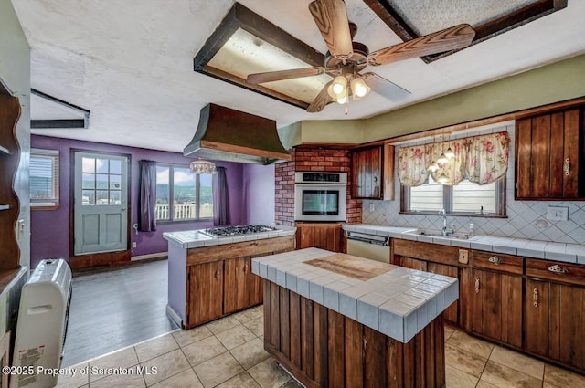 kitchen featuring a kitchen island, tile counters, appliances with stainless steel finishes, and custom exhaust hood