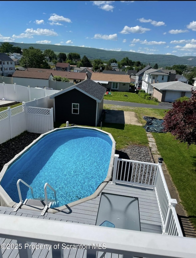 view of pool with a fenced in pool, a shed, an outbuilding, a fenced backyard, and a residential view