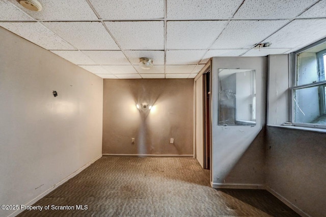empty room featuring a drop ceiling, carpet floors, and baseboards