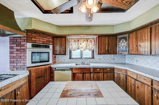 kitchen featuring dishwashing machine, stainless steel oven, a sink, and decorative backsplash