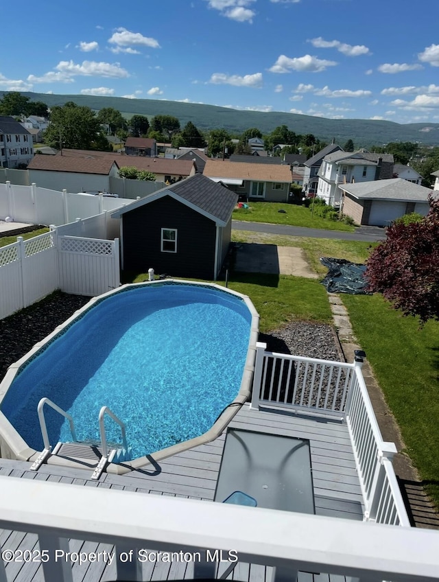 view of swimming pool featuring an outdoor structure, a residential view, a fenced backyard, a storage unit, and a fenced in pool