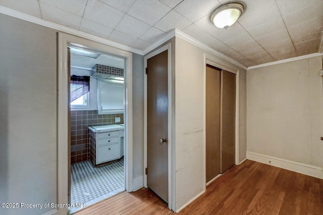 hall with ornamental molding, baseboards, and wood finished floors