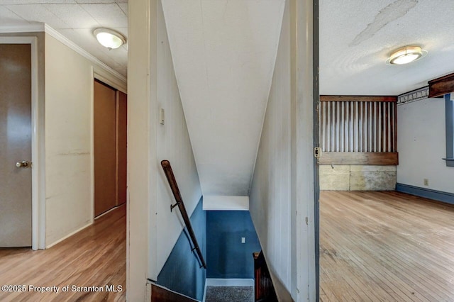stairs with baseboards, ornamental molding, and wood finished floors
