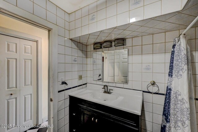 full bathroom featuring tile walls, a shower with shower curtain, backsplash, and vanity
