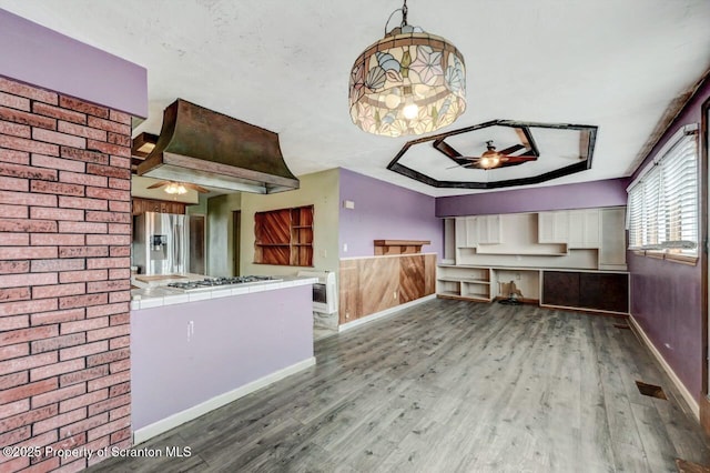 kitchen with tile countertops, wood finished floors, stainless steel appliances, and a ceiling fan