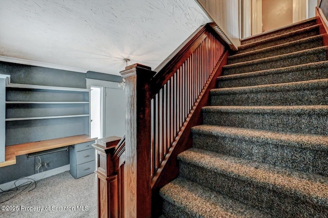 stairway with carpet floors, a textured ceiling, crown molding, and built in desk
