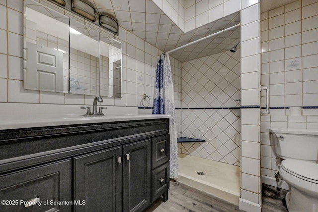 full bathroom with a stall shower, vanity, and tile walls