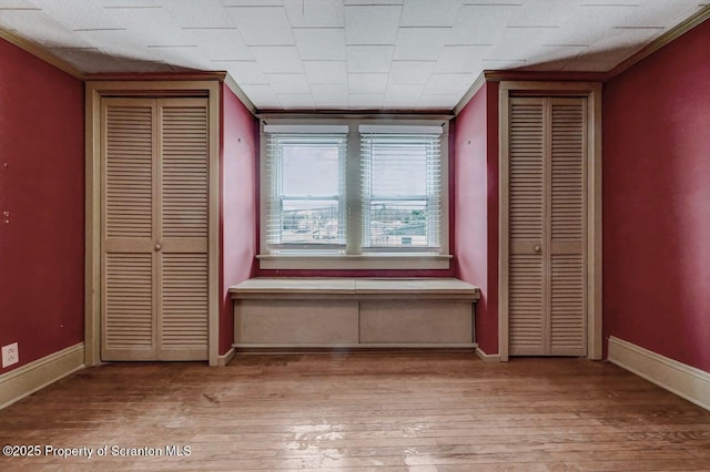 unfurnished bedroom with ornamental molding, hardwood / wood-style flooring, and baseboards