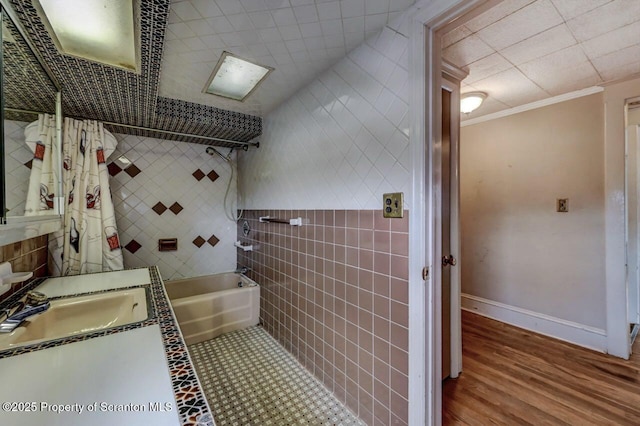 full bathroom featuring crown molding, vanity, wood finished floors, baseboards, and tile walls