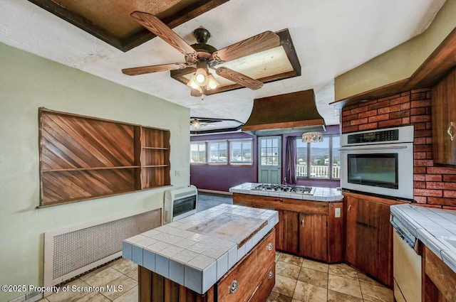 kitchen featuring tile counters, stainless steel oven, heating unit, radiator, and gas stovetop