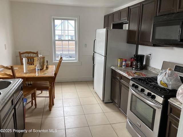 kitchen with dark brown cabinetry, light stone counters, light tile patterned floors, and stainless steel range with gas cooktop