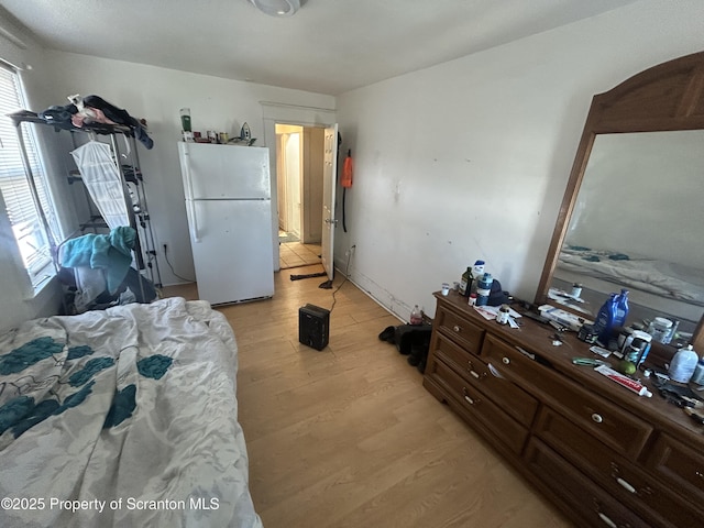 bedroom with light wood-type flooring and white fridge