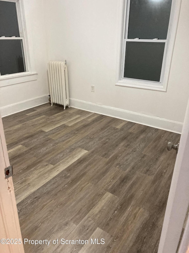 empty room featuring dark hardwood / wood-style floors and radiator heating unit