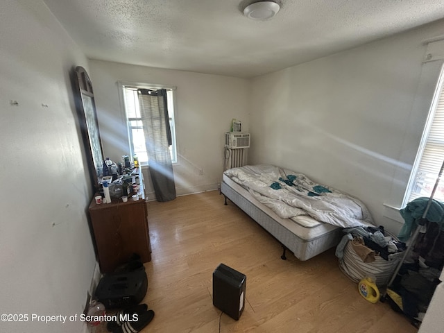 bedroom with light hardwood / wood-style floors and a textured ceiling