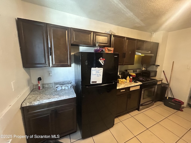 kitchen with dark brown cabinets, black refrigerator, light tile patterned floors, range with gas cooktop, and a textured ceiling