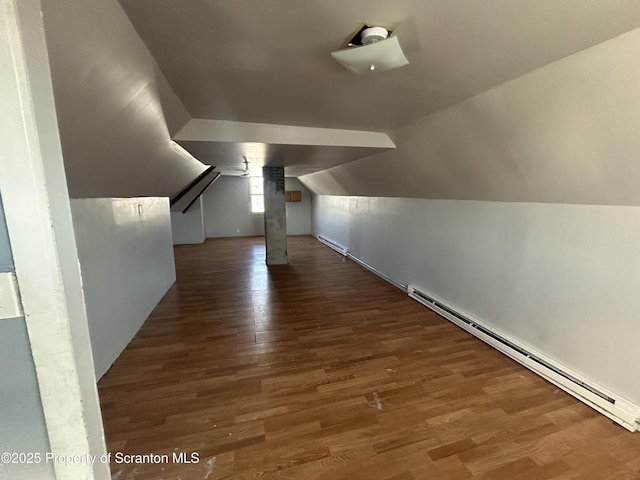 additional living space featuring a baseboard radiator, dark hardwood / wood-style flooring, and vaulted ceiling