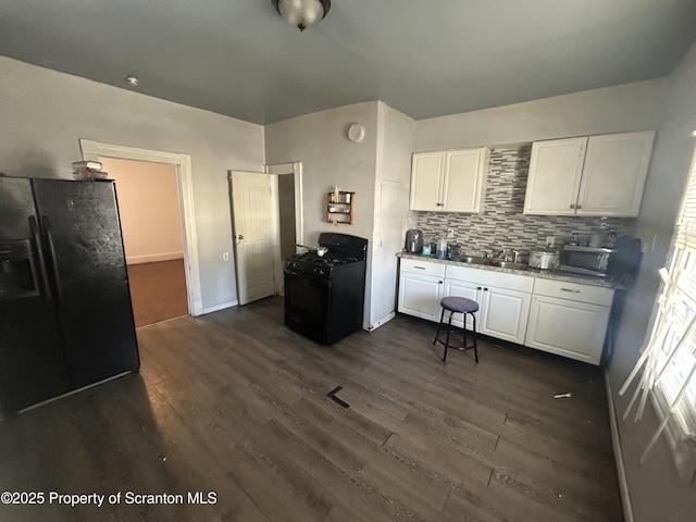 kitchen featuring black appliances, backsplash, white cabinetry, and dark hardwood / wood-style flooring