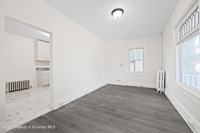 1303 Main St, Pittston, PA 18640 - empty room with radiator and dark wood-style flooring