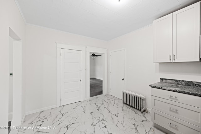1303 Main St, Pittston, PA 18640 - kitchen with radiator heating unit, dark countertops, ornamental molding, light marble finish flooring, and white cabinetry