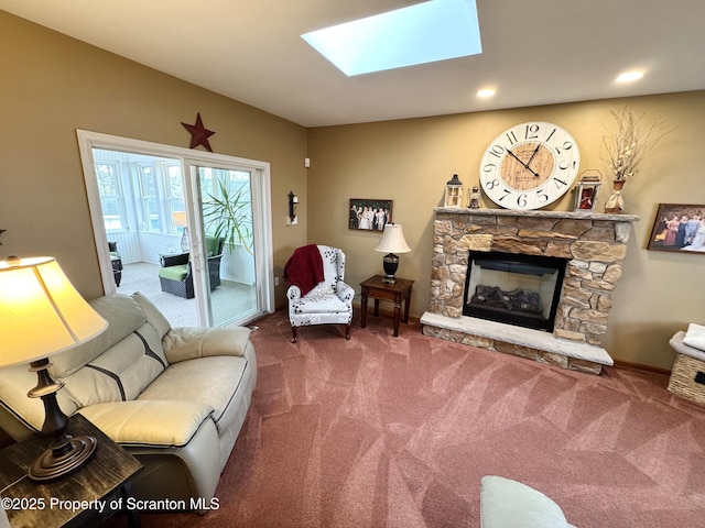 carpeted living area with a stone fireplace, a skylight, and recessed lighting