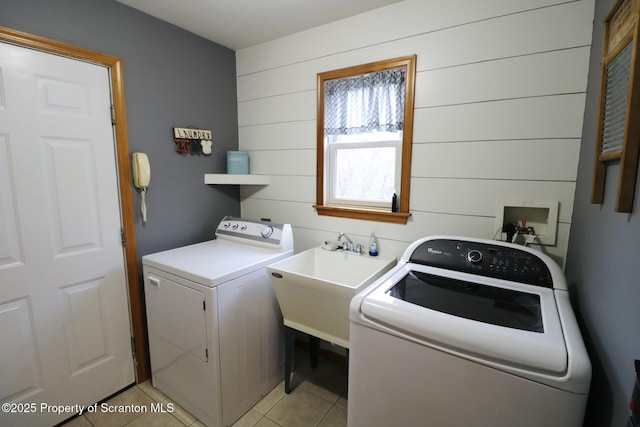 laundry area featuring independent washer and dryer, light tile patterned floors, and wood walls