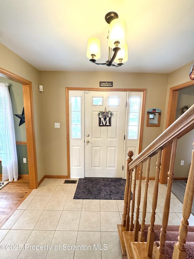 entrance foyer with light tile patterned floors, a chandelier, and baseboards