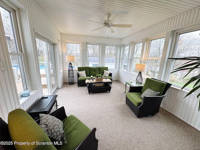 sunroom featuring ceiling fan, carpet flooring, outdoor lounge area, and a water view