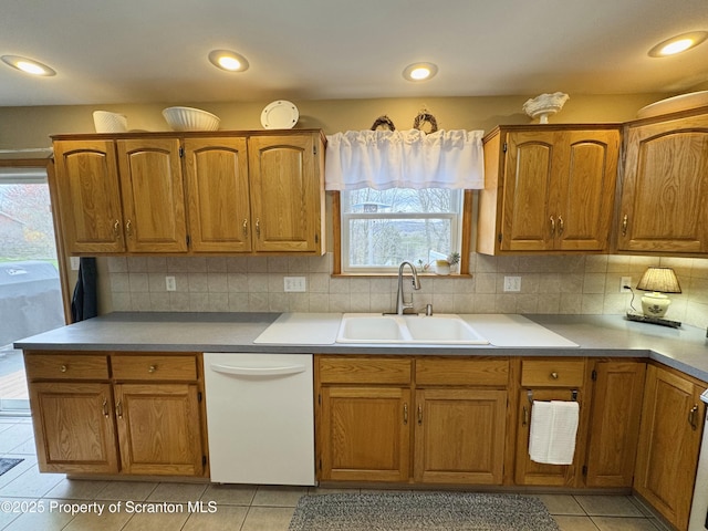 kitchen featuring dishwasher, a sink, brown cabinets, light tile patterned floors, and recessed lighting