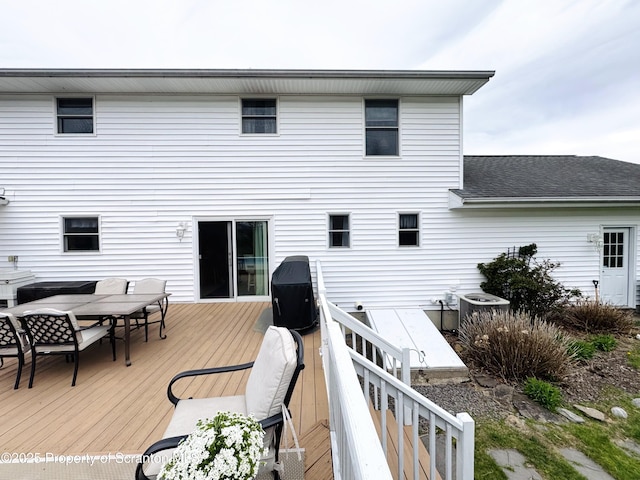 rear view of property featuring outdoor dining area, a wooden deck, central air condition unit, and roof with shingles