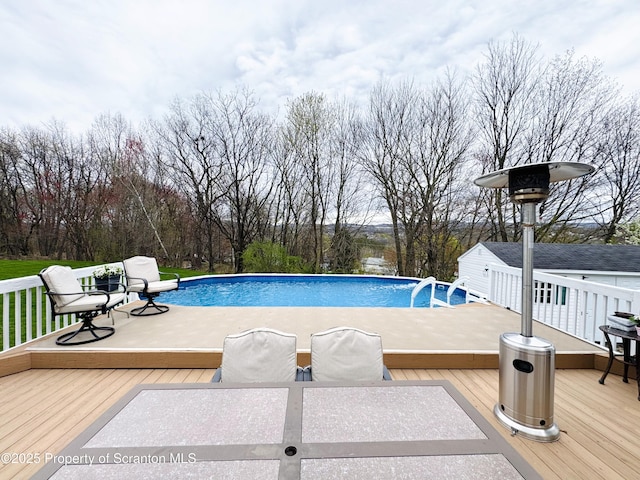 swimming pool featuring a deck, outdoor dining space, and view of scattered trees
