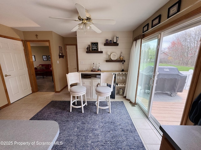 dining space featuring bar, light tile patterned floors, and a ceiling fan