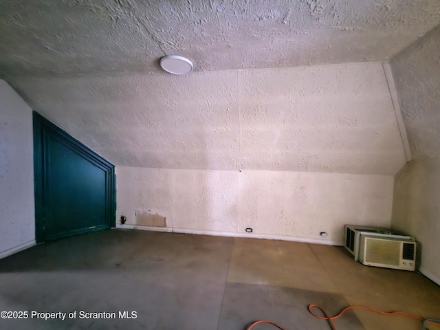 bonus room featuring vaulted ceiling, a wall mounted AC, and a textured ceiling