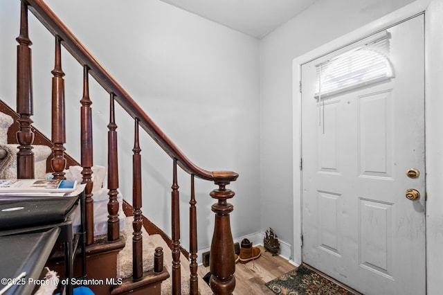 foyer entrance with stairs, baseboards, and wood finished floors