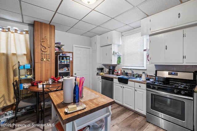 kitchen with stainless steel appliances, light wood-style flooring, white cabinetry, a sink, and a drop ceiling