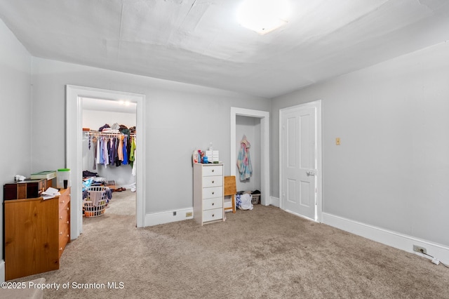 carpeted bedroom with baseboards, a walk in closet, and a closet