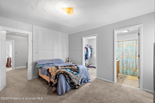 bedroom with baseboards, a walk in closet, and light colored carpet