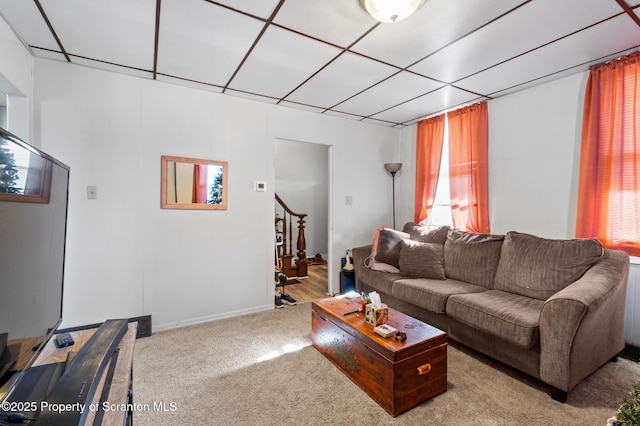 living room with radiator heating unit, stairs, and light colored carpet